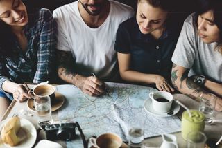 A group of friends sitting in a cafe planning a route on a map