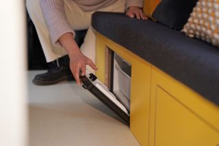 A woman opening the fridge under the bench