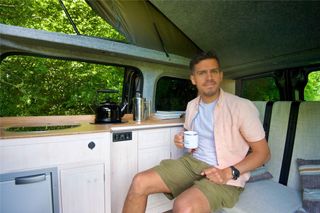 Wild Drives founder Lewis Nyman sitting in Eve the electric campervan