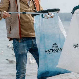A man walking along a beach with a litter picking kit