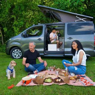 Three people enjoying a picnic infront of the van